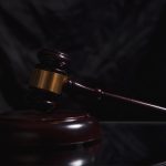 Gavel resting next to a signed legal settlement contract on a wooden desk - how do lawyers negotiate settlements​