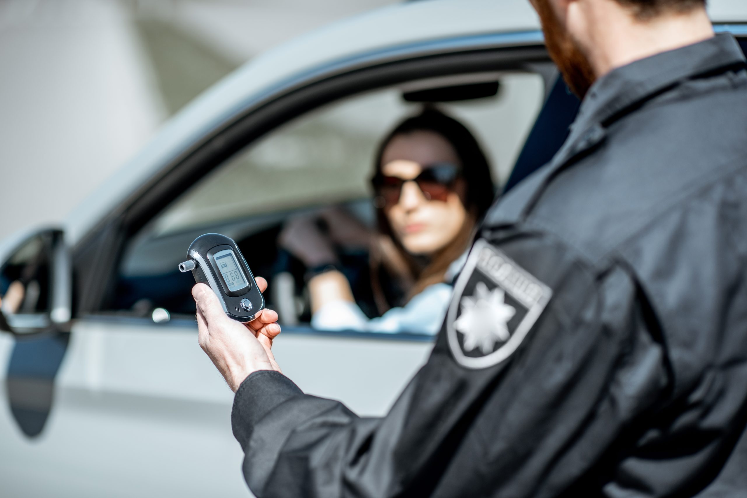 Police officer checking a breathalyzer during a DWI traffic stop.